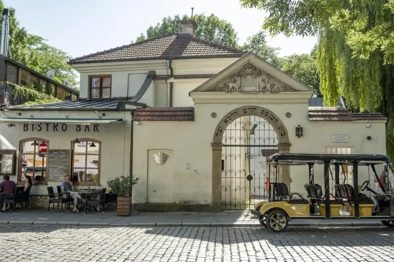 Kazimierz, Kraków. Bistro Bar i zabytkowa brama z hebrajskimi napisami. Obok żółty meleks, idealny na zwiedzanie.